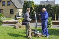 Begau, Alter Römerweg, Foto-Nr. 36, 02.05.2009<br />Kunstschmiedearbeiten<br />Der Meister erklärt sein Kunstwerk. Fußballspieler mit Ball im Stadion mit Tribünen.